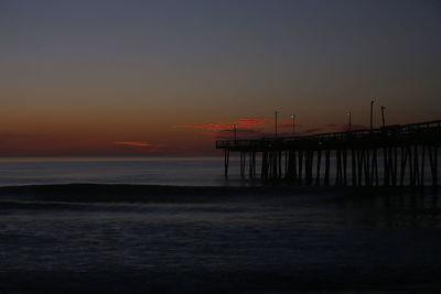 Silhouette pier on beach against sky during sunset