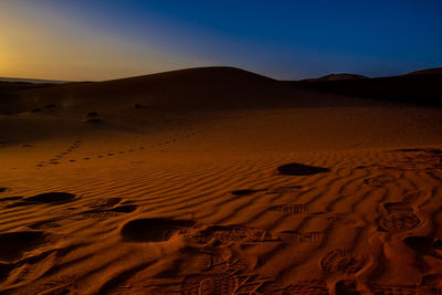 Scenic view of desert against clear sky during sunset