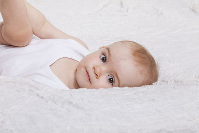 Close-up of baby girl lying on bed at home