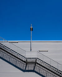 Low angle view of street light against building against clear blue sky
