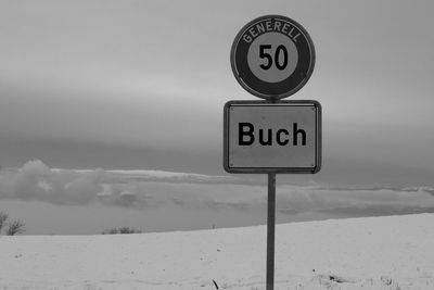 Road sign against sky during winter