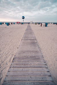 Surface level of pier on beach against sky