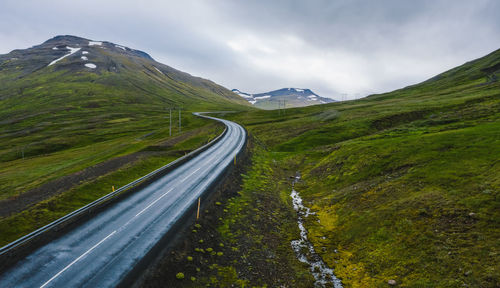 Road amidst green landscape against sky