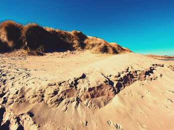 Scenic view of desert against clear blue sky