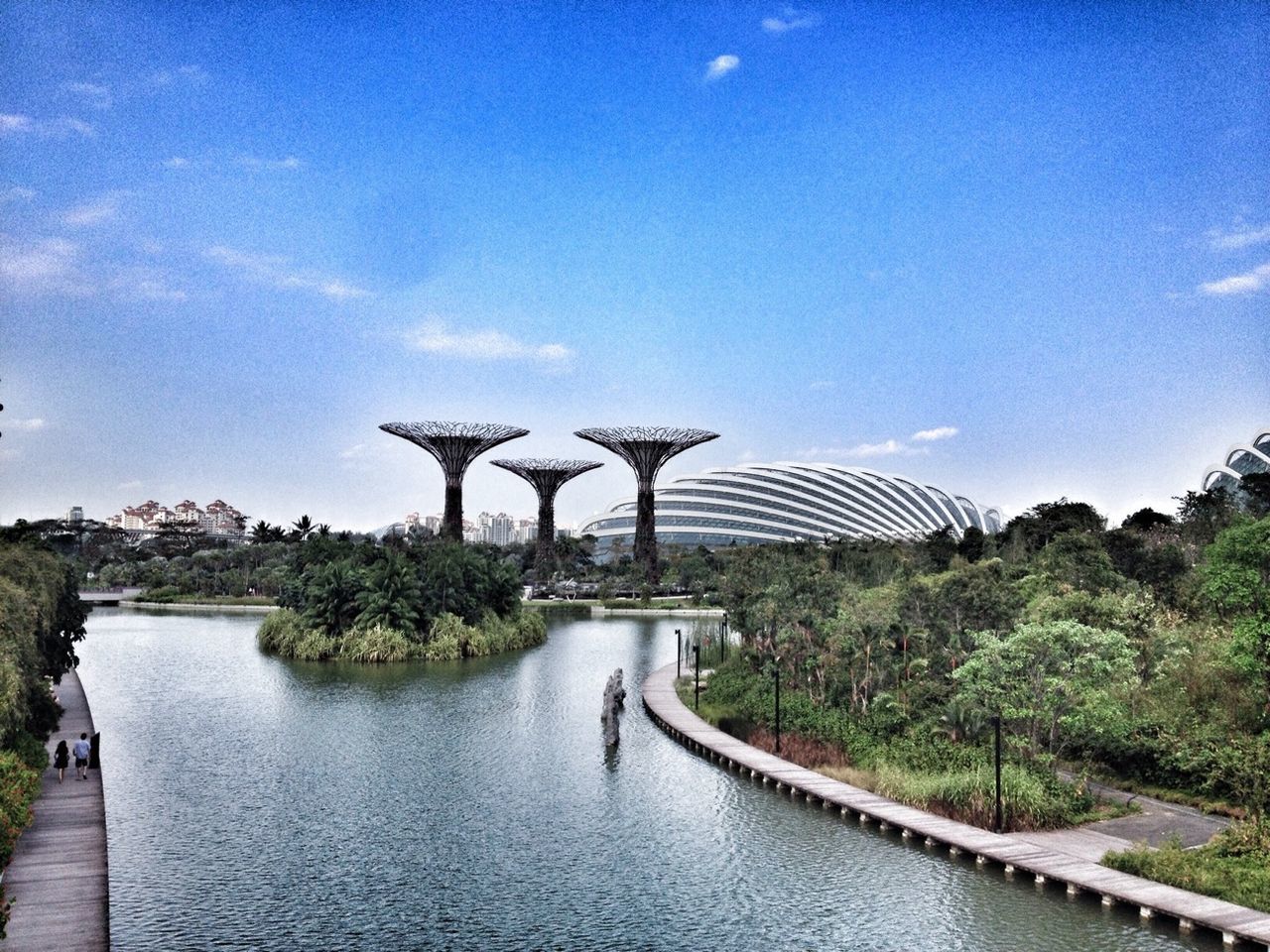 built structure, water, tree, architecture, sky, blue, tranquility, nature, plant, tranquil scene, building exterior, sunlight, river, park - man made space, growth, day, beauty in nature, scenics, outdoors, grass