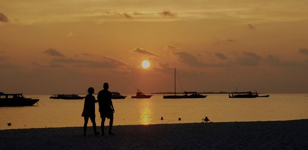 Silhouette couple walking at beach