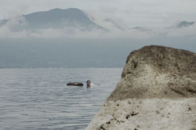 Man swimming in sea against sky