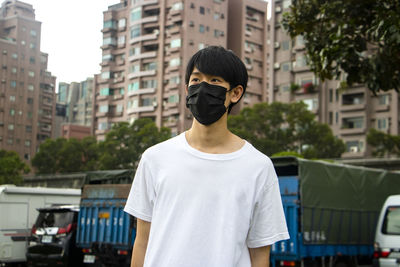 Portrait of young man standing on street in city