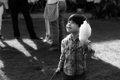 Cute boy looking up while holding candyfloss outdoors