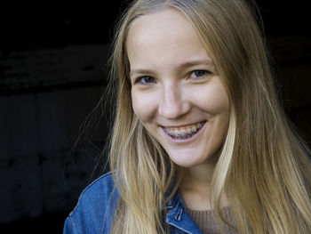 Portrait of smiling woman against black background