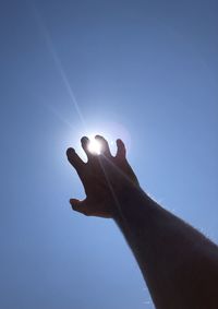 Low angle view of hand against clear blue sky