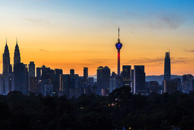 Modern buildings in city against sky during sunset