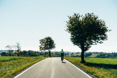 Empty road amidst trees against clear sky