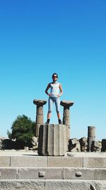 Low angle view of woman standing against clear blue sky