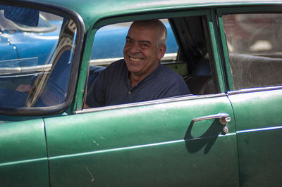 Portrait of man sitting on car window