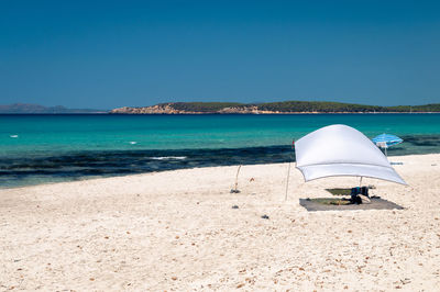 Lifeguard hut on beach against clear blue sky