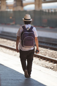 Rear view of man walking on railway platform