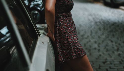 Midsection of woman standing by car