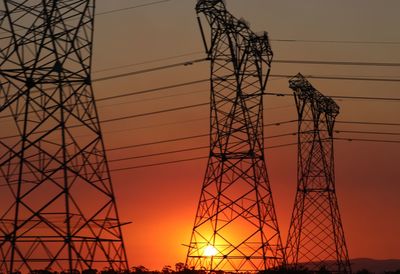 Low angle view of silhouette electricity pylon against sky during sunset