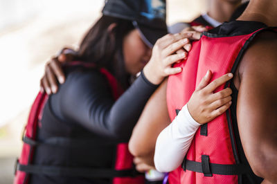 Friends wearing life jackets standing with arm around