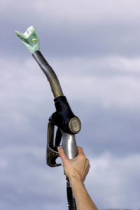 Close-up of hand holding camera against sky