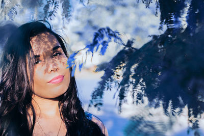 Portrait of woman by tree in sunny day