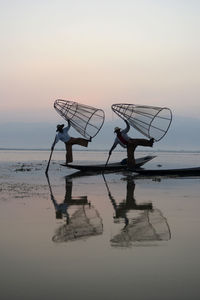 Men fishing in lake at sunset