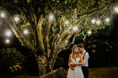 Couple standing against plants and trees