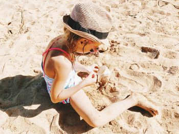 Girl sitting at sandy beach on sunny day