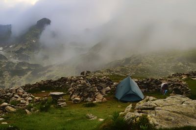 Tent on rocky mountain against sky