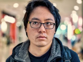 Portrait of young asian man in eyeglasses against illumination.