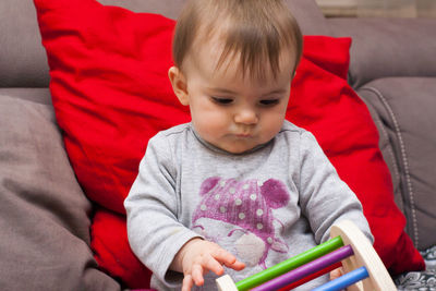 Cute baby girl sitting on sofa at home