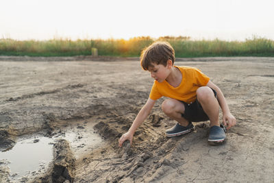 Side view of boy sitting on beach