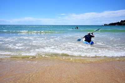 Man in boat on shore at beach against sky