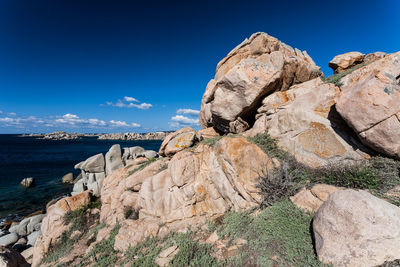 Rock formations by sea against blue sky