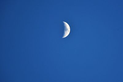 Low angle view of half moon against clear blue sky