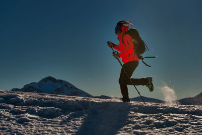 Woman with umbrella against mountain during winter