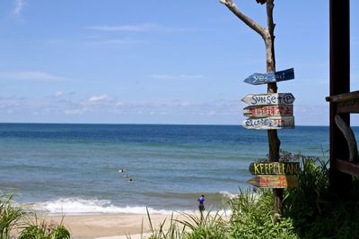 Sign at beach against blue sky