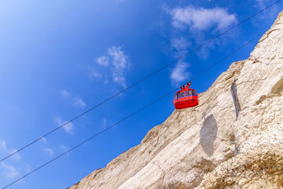Low angle view on bright red cable car wagon against blue sky