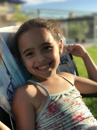 Close-up portrait of smiling girl sitting outdoors