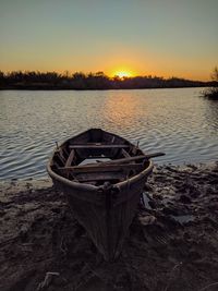 Abandoned boat moored in lake against sky during sunset
