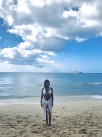 Full length of woman standing on beach against sky