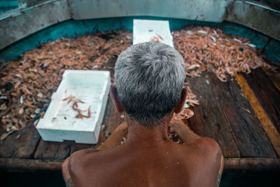 Rear view of shirtless man sitting outdoors
