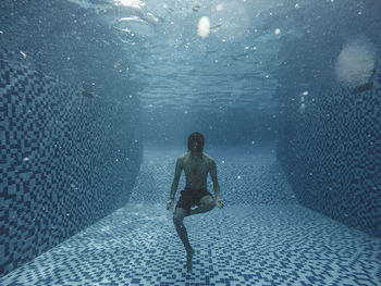 Shirtless man swimming in pool