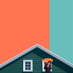 Man standing by building against clear sky