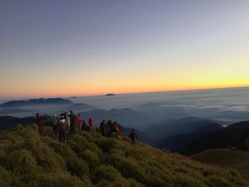 People on mountain against sky during sunset