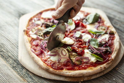 Close-up of pizza on table being cut