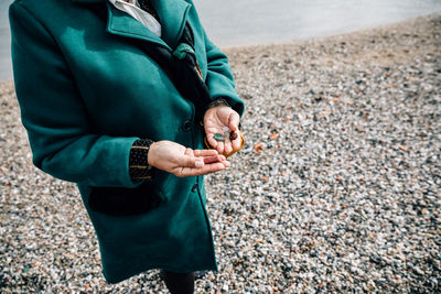 Detail of the hands of a woman showing some stones by the sea