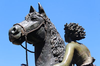 Low angle view of statues against clear blue sky