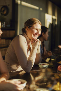 Happy woman leaning on dining table at retreat center